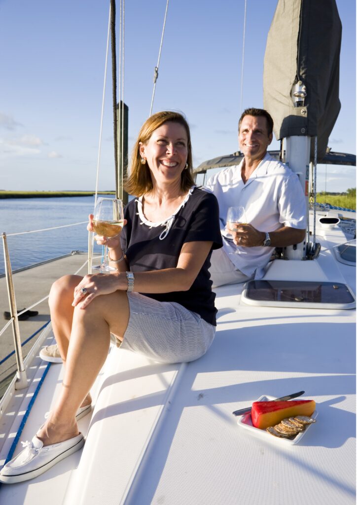 Two people sitting on a sailboat enjoying a drink